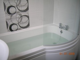 Modern white bathroom suite with quadrant curved bath fitted by Aqua Systems