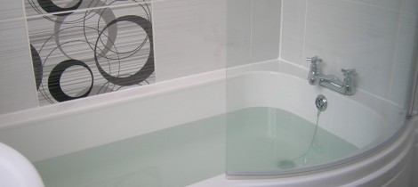 Modern white bathroom suite with quadrant curved bath fitted by Aqua Systems